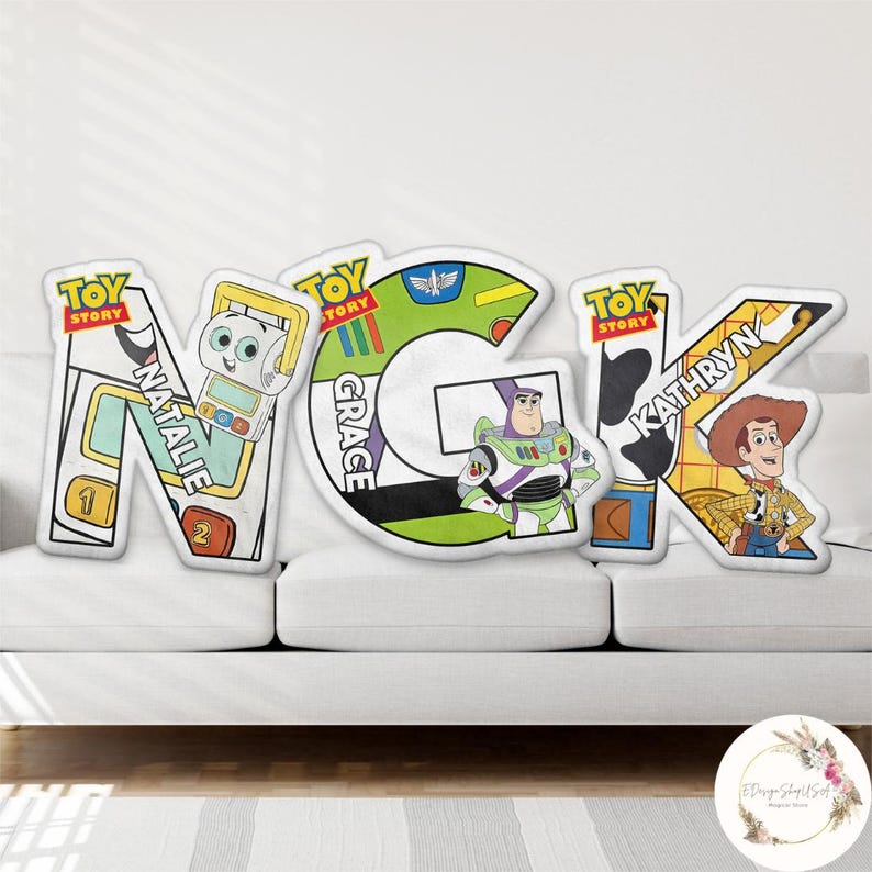 May include: Custom Toy Story themed pillows spelling out the letters N, G, and K. Each letter features a different character: Natalie, Grace, and Kathryn. The pillows are white with colorful character designs.