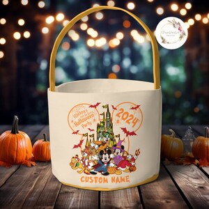 May include: A white canvas trick-or-treat bag with a yellow handle. The bag features a Mickey Mouse head silhouette with a  castle and Mickey Mouse characters inside. The text on the bag reads "Mickey's Not-So-Scary Halloween Party 2024" and "CUSTOM NAME".