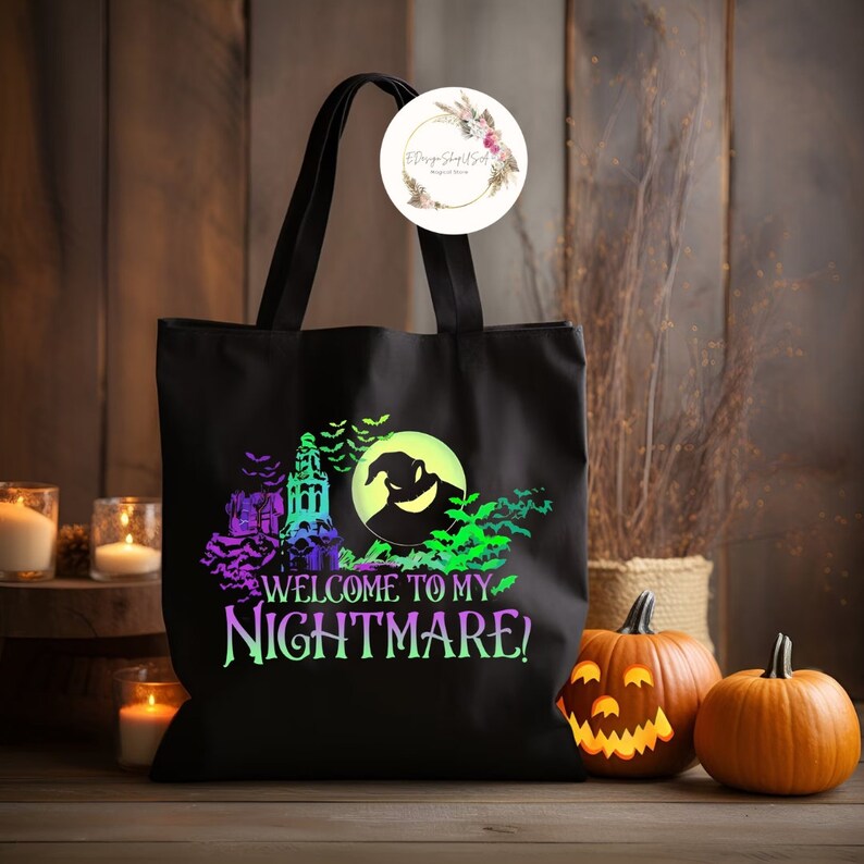 K&ouml;nnte beinhalten: Schwarze Tragetasche mit Halloween-Design. Das Design zeigt ein Spukhaus, Flederm&auml;use und den Schriftzug "WELCOME TO MY NIGHTMARE!" in Lila und Gr&uuml;n. Zwei K&uuml;rbisse und Kerzen sind im Hintergrund.