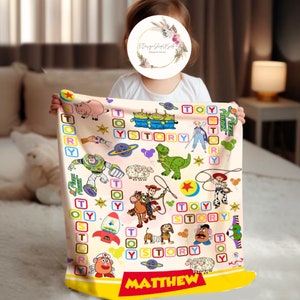 Puede incluir: Una manta de beb&eacute; rosa y amarilla con tem&aacute;tica de Toy Story. La manta presenta personajes de la pel&iacute;cula, incluidos Woody, Buzz Lightyear y Rex. La manta est&aacute; personalizada con el nombre "MATTHEW".