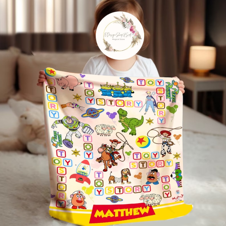Puede incluir: Una manta de beb&eacute; rosa y amarilla con tem&aacute;tica de Toy Story. La manta presenta personajes de la pel&iacute;cula, incluidos Woody, Buzz Lightyear y Rex. La manta est&aacute; personalizada con el nombre "MATTHEW".