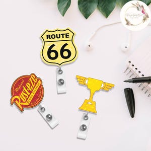 Puede incluir: Tres portatarjetas retr&aacute;ctiles con diferentes dise&ntilde;os. Uno es un letrero amarillo de la Ruta 66, otro es un trofeo amarillo con alas y el tercero es un logotipo de ung&uuml;ento para parachoques Rusteze rojo y amarillo.