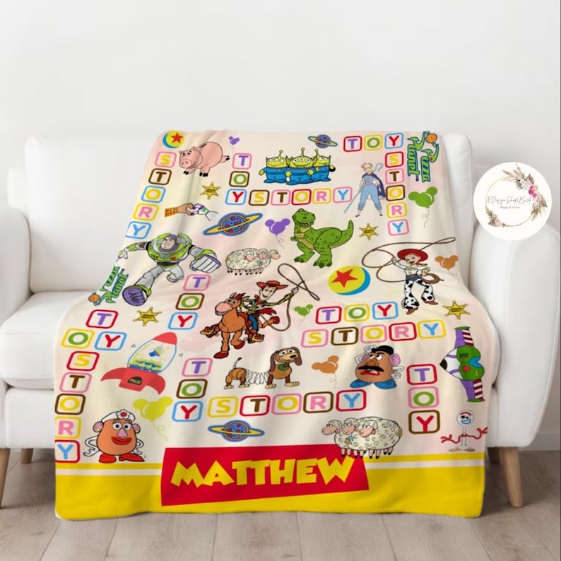 Puede incluir: Una manta de forro polar de color crema con tem&aacute;tica de Toy Story. La manta presenta personajes de la pel&iacute;cula, incluidos Woody, Buzz Lightyear y el Sr. Potato Head. La manta est&aacute; decorada con bloques coloridos que deletrean "Toy Story". La manta tiene un borde amarillo y una franja roja con el nombre "MATTHEW" impreso en ella.