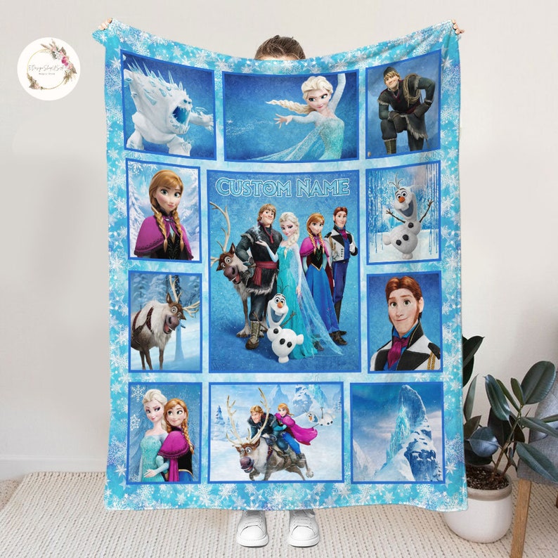 May include: A blue fleece blanket with a patchwork design featuring characters from the movie Frozen. The blanket has a snowflake pattern and includes images of Elsa, Anna, Kristoff, Olaf, Sven, and the snow monster. The text "CUSTOM NAME" is printed in the center of the blanket.