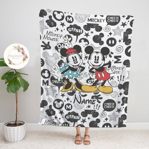 Może przedstawiać: Czarno-biały koc z kresk&oacute;wkowym wizerunkiem Myszki Miki i Minnie Mouse. Koc ma r&oacute;żne bazgroły i tekst, w tym "Mickey Mouse", "Gush", "Cheese" i "Name".