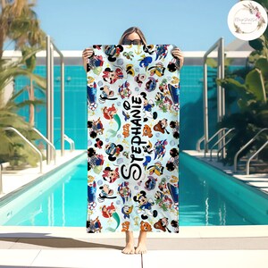 Puede incluir: Una toalla de playa azul con un patr&oacute;n colorido de personajes de Disney, incluyendo Mickey Mouse, Minnie Mouse, Ariel y Stitch. La toalla tiene el nombre "Stephanie" impreso en ella.