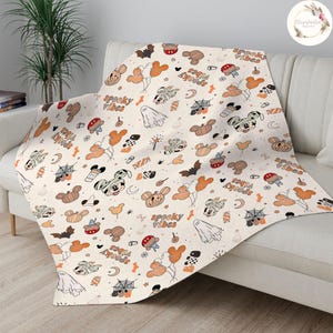 May include: A white throw blanket with a Halloween-themed pattern featuring Mickey Mouse, pumpkins, bats, and the text "Spooky Vibes" and "Boo Ya'll" repeated throughout.