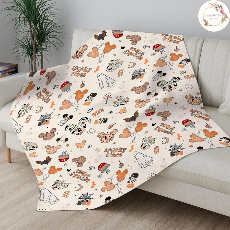 May include: A white throw blanket with a Halloween-themed pattern featuring Mickey Mouse, pumpkins, bats, and the text "Spooky Vibes" and "Boo Ya'll" repeated throughout.