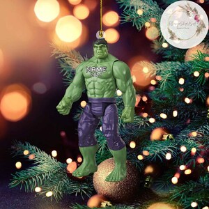 K&ouml;nnte beinhalten: Gr&uuml;ner Hulk Weihnachtsbaumschmuck mit einem Namen und dem Jahr 2024 auf der Vorderseite.