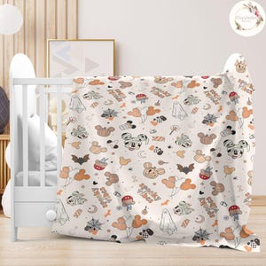 May include: A white baby blanket with a Halloween-themed pattern featuring Mickey Mouse and other Disney characters. The pattern includes pumpkins, ghosts, bats, candy corn, and the text "Spooky Vibes" and "Sweet Treats".