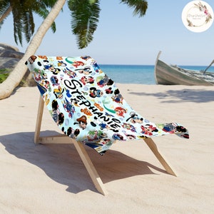 Puede incluir: Una toalla de playa blanca con un fondo azul que presenta una variedad de personajes de Disney, incluidos Mickey Mouse, Minnie Mouse, Donald Duck, Goofy y otros. La toalla tiene el nombre "Stephanie" escrito en letras negras.