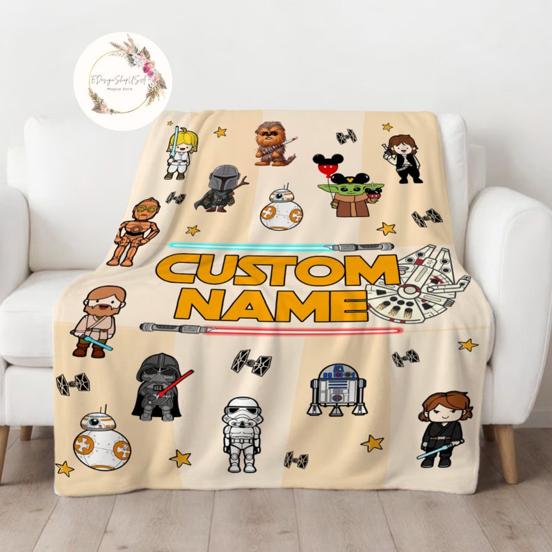 May include: A beige fleece blanket with a Star Wars theme. It features various characters from the franchise, including Darth Vader, Yoda, Chewbacca, and R2-D2. The blanket also has the text "CUSTOM NAME" in yellow letters.