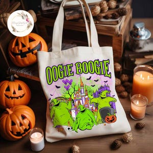 Puede incluir: Una bolsa de lona blanca con un estampado gr&aacute;fico verde, morado y negro de Oogie Boogie de Pesadilla antes de Navidad. El gr&aacute;fico presenta a Oogie Boogie frente a un castillo con murci&eacute;lagos volando alrededor.