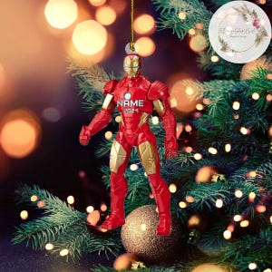 K&ouml;nnte beinhalten: Roter und goldener Iron Man Weihnachtsbaumschmuck mit dem Namen "NAME" und dem Jahr "2024" auf der Brust.