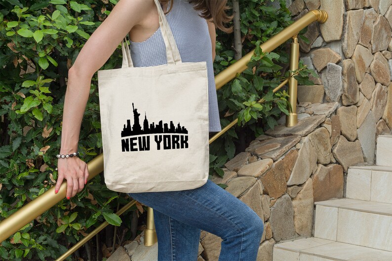 May include: A white canvas tote bag with a black silhouette of the New York City skyline and the text "NEW YORK" printed on the front.