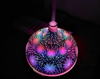 May include: A round, white ceramic essential oil diffuser with a colourful, abstract design. The diffuser has a light that changes colours and emits a fine mist.
