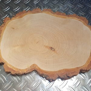 Op de afbeelding: Een natuurlijke houten schijf met een lichtbruin interieur en een donkerdere, getextureerde schorsrand. De houtnerf is zichtbaar en toont de groeiringen. De vorm is onregelmatig, met een rustiek, organisch gevoel.