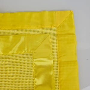 May include: A yellow waffle weave baby blanket with a satin trim. The blanket has a soft, textured feel and is perfect for cuddling.