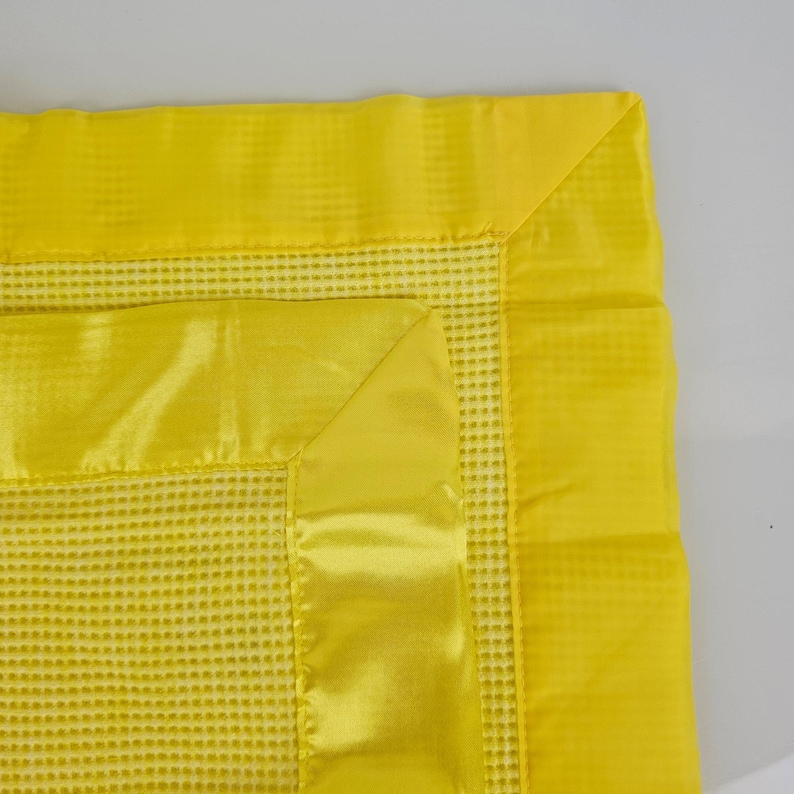 May include: A yellow waffle weave baby blanket with a satin trim. The blanket has a soft, textured feel and is perfect for cuddling.