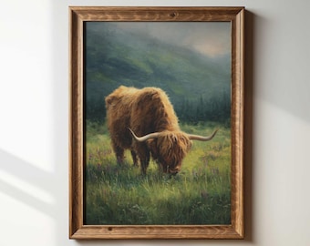 Könnte beinhalten: Ein gerahmter Druck einer Hochlandkuh, die auf einer Wiese grast. Das Kunstwerk zeigt eine braune, zottelige Kuh mit langen Hörnern vor dem Hintergrund grüner Hügel und eines nebligen Himmels. Der Rahmen ist aus dunklem Holz.