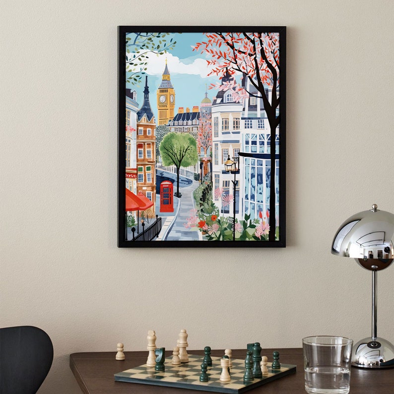 May include: A framed illustration of a street scene in London, England. The image features a red telephone booth, a red awning, and a view of Big Ben in the distance. The buildings are painted in a colorful style with a whimsical feel.