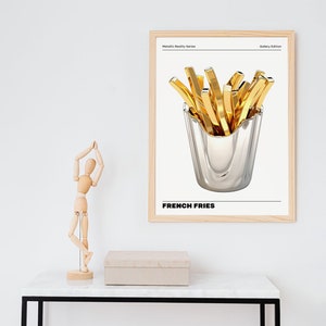 May include: A framed print with a gold metallic design of french fries in a silver container. The print has the text "Metallic Reality Series" and "Gallery Edition" at the top and "FRENCH FRIES" at the bottom.