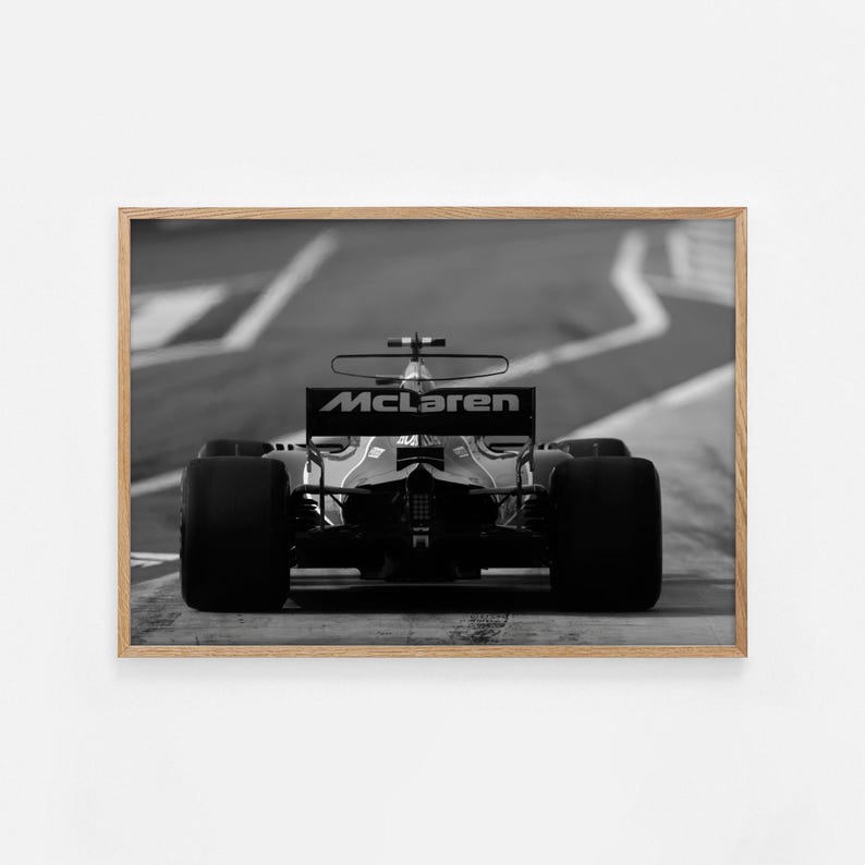 Puede incluir: Una fotograf&iacute;a en blanco y negro de un coche de carreras de F&oacute;rmula 1 McLaren conduciendo en una pista. El coche est&aacute; de espaldas a la c&aacute;mara y el logotipo de McLaren es visible en el aler&oacute;n trasero.
