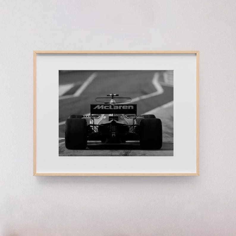 Puede incluir: Una fotograf&iacute;a en blanco y negro de un coche de carreras de F&oacute;rmula 1 McLaren en una pista. El coche est&aacute; de cara a la c&aacute;mara y el logotipo de McLaren es visible en el aler&oacute;n trasero.
