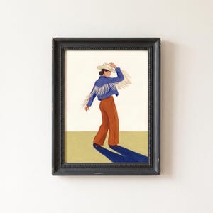 Puede incluir: Una lámina enmarcada que representa una figura con sombrero de vaquero blanco, chaqueta azul con flecos largos y pantalones color óxido. La figura se encuentra sobre un suelo color oliva claro con fondo crema, proyectando una larga sombra azul.