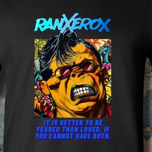 May include: A black short-sleeved t-shirt featuring a graphic of the character Ranxerox with dark hair and red-tinted glasses. The text above reads RANXEROX and below reads IT IS BETTER TO BE FEARED THAN LOVED, IF YOU CANNOT HAVE BOTH in blue letters.