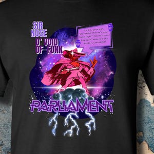 May include: A black short-sleeve t-shirt featuring a graphic of Sir Nose D'Void of Funk from Parliament. The design includes a purple speech bubble with text, a cosmic background, and lightning bolts. The text reads Sir Nose D'Void of Funk and Parliament.