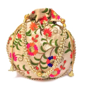 May include: A round, cream-colored drawstring bag with a floral pattern in shades of pink, orange, green, and blue. The bag has a gold beaded trim and a long, pearl-like tassel.