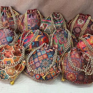 May include: A collection of colorful drawstring bags with intricate patterns and beaded trim. The bags are made of fabric and have a traditional Indian design.