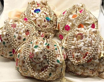 May include: Five white drawstring bags with gold embroidery and pearl embellishments. The bags have floral patterns in shades of pink, green, orange, and blue.