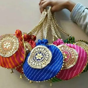 May include: A set of six colorful drawstring bags with round, embellished closures. The bags are made of a striped fabric and have gold chains attached.
