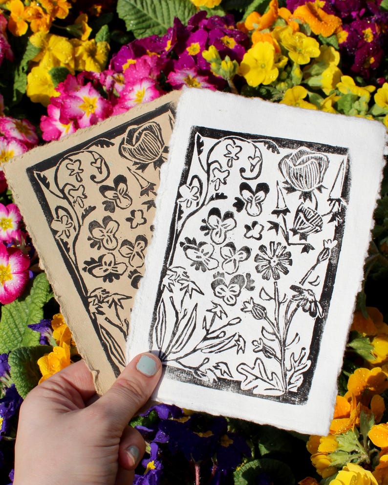 Pode incluir: Duas impress&otilde;es de lin&oacute;leo em preto e branco com desenhos florais. As impress&otilde;es est&atilde;o em papel de cores diferentes, uma em papel castanho e a outra em papel branco.