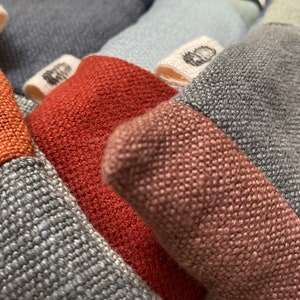 Könnte beinhalten: Nahaufnahme eines mehrfarbigen Stoffes mit unterschiedlichen Texturen. Der Stoff ist aus einem gewebten Material gefertigt und hat eine Vielzahl von Farben, darunter Braun, Rot, Blau und Grau.