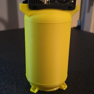 May include: A yellow 3D-printed air compressor model. The cylindrical tank has a black top with two silver cylinders and a black grill. The model has a base with four feet.
