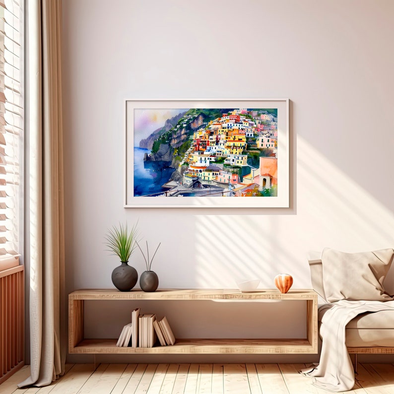 May include: A watercolour painting of a colourful Italian village built on a hillside overlooking the sea. The buildings are painted in shades of yellow, orange, pink, and blue. The sea is a deep blue, and the sky is a light blue.