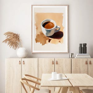 Puede incluir: Una pintura de acuarela enmarcada de una taza de caf&eacute; blanca con un l&iacute;quido marr&oacute;n en su interior, sentada sobre una superficie marr&oacute;n claro. La taza proyecta una sombra sobre la superficie.