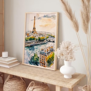 Puede incluir: Una pintura de acuarela de la Torre Eiffel en Par&iacute;s, Francia. La pintura muestra la torre en la distancia con un r&iacute;o y edificios en primer plano. La pintura est&aacute; enmarcada en un marco de madera claro y est&aacute; colgada en una pared.