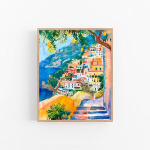 May include: Watercolour painting of a coastal Italian village with colourful buildings cascading down a hillside. A tree with lemons hangs over the scene. The artwork is framed in a light wood frame.