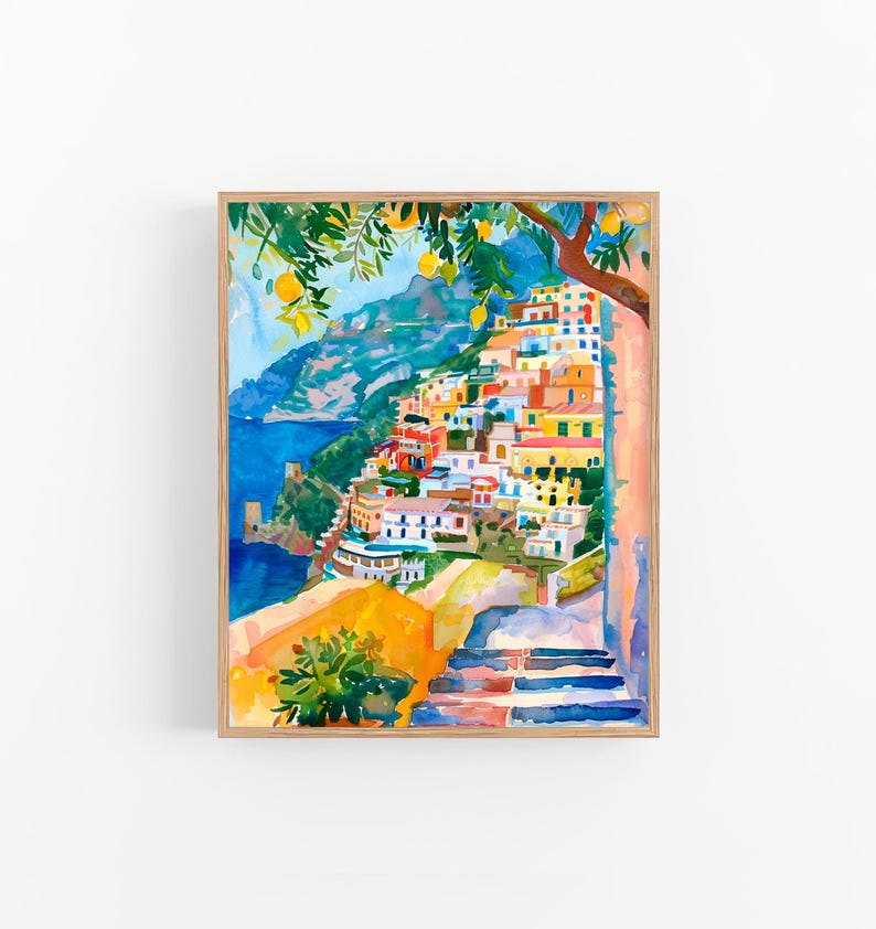 May include: Watercolour painting of a coastal Italian village with colourful buildings cascading down a hillside. A tree with lemons hangs over the scene. The artwork is framed in a light wood frame.