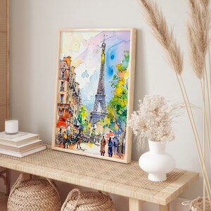 Puede incluir: Una pintura de acuarela de la Torre Eiffel en Par&iacute;s, Francia. La pintura est&aacute; enmarcada en un marco de madera clara y est&aacute; colgada en una pared sobre un banco de madera. El banco tiene un asiento de rat&aacute;n tejido y est&aacute; decorado con dos cestas tejidas.