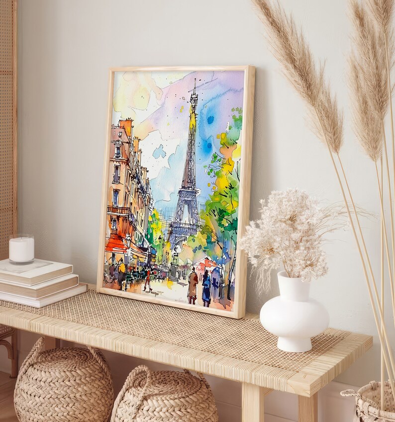 Puede incluir: Una pintura de acuarela de la Torre Eiffel en Par&iacute;s, Francia. La pintura est&aacute; enmarcada en un marco de madera clara y est&aacute; colgada en una pared sobre un banco de madera. El banco tiene un asiento de rat&aacute;n tejido y est&aacute; decorado con dos cestas tejidas.