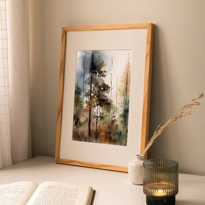 May include: A framed watercolor painting of a forest scene with trees in shades of brown, green, and blue. The painting is on a white table with a book and a candle holder.