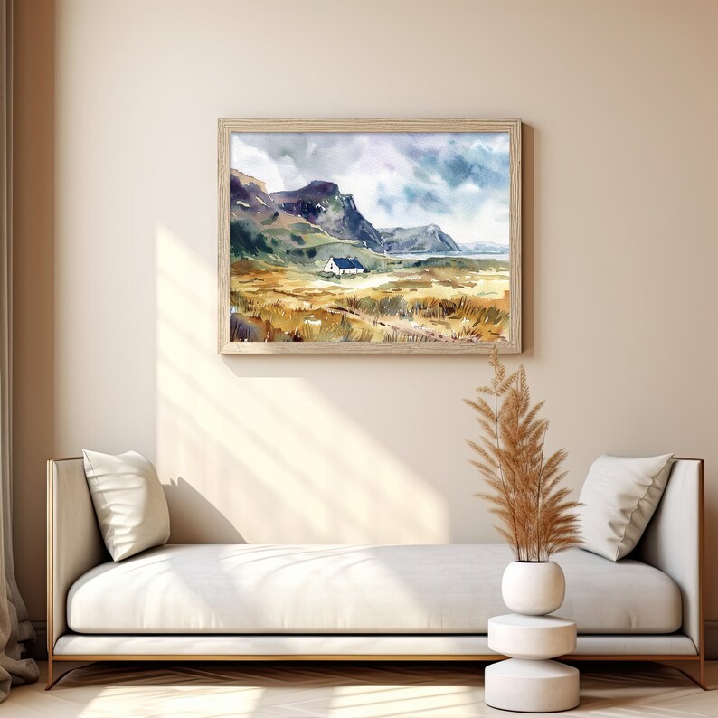 Pu&ograve; includere: Un dipinto ad acquerello di un paesaggio con una piccola casa in lontananza. Il dipinto &egrave; incorniciato in una cornice di legno chiaro e appeso a una parete beige. Un divano bianco con cuscini &egrave; in primo piano, e una pianta di erba secca &egrave; in un vaso bianco su un piedistallo bianco.