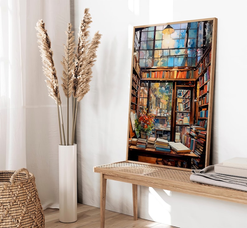 May include: A painting depicting the interior of a bookshop, featuring a large window, wooden shelves stacked with books, and a table with books and flowers. The painting is framed in a light wood frame.