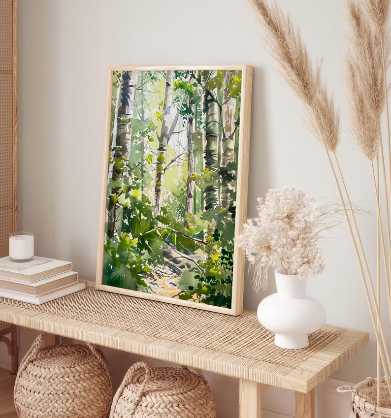 May include: A watercolor painting of a forest scene with tall trees and green foliage. The painting is framed in a light wood frame and is hanging on a wall.