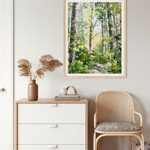 May include: A framed watercolor painting of a forest scene with tall trees and green foliage. The painting is in a light wood frame and is hanging on a white wall.